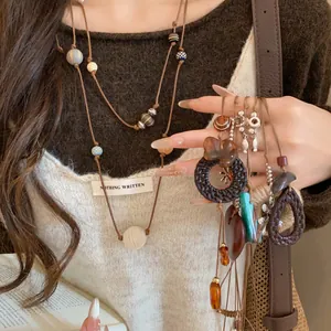 Détail du long collier de style néo-chinois avec cordon en cuir et perles de bois sur mannequin