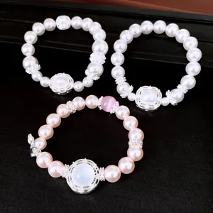 Primer plano de tres pulseras elásticas de perlas de circón de lujo en blanco y rosa.