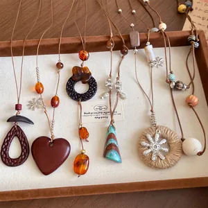 Détail de divers colliers à pendentifs en bois et en résine de style bohème sur plateau.