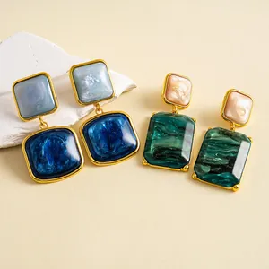 Nahaufnahme von Vintage-Ohrringen aus Kunstharz in Blau und Grün mit Goldrahmen.