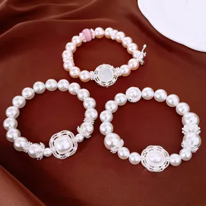 Vista detallada de elegantes pulseras de perlas con centros de circón sobre seda marrón
