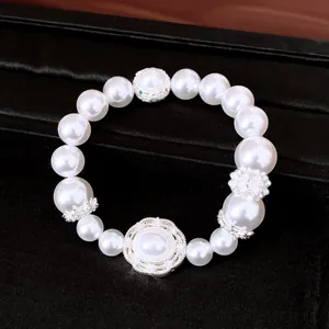 Elegante pulsera elástica de perlas blancas con detalles decorativos plateados