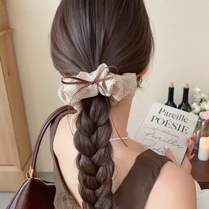 Detail of a retro polka dot scrunchie with bow tie used on a braided hairstyle