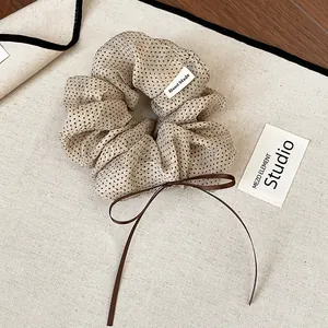 Close-up of a vintage beige polka dot scrunchie with a brown ribbon bow detail.