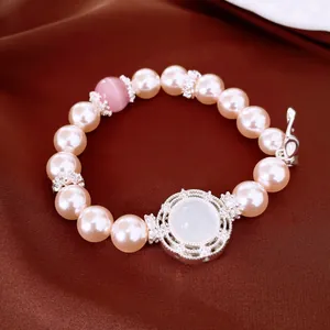 Elegante pulsera elástica de perlas y circonitas sobre un fondo de satén marrón.