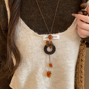 Vue détaillée d'un long collier pendentif de style néo-chinois avec cordon en cuir et perles d'ambre