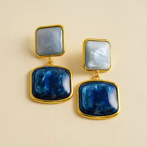 Detailaufnahme von blauen Vintage-Resin-Ohrringen mit Marmormuster im Goldrahmen