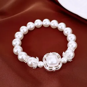 Primer plano de una lujosa pulsera elástica de perlas y circón sobre seda marrón