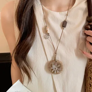 Gros plan d'un collier long à double couche avec perles en bois et pendentifs fleurs