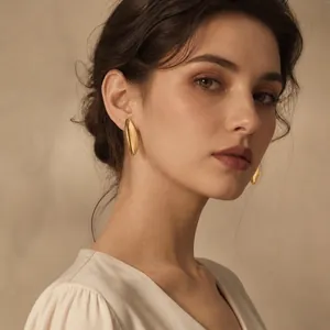 Detailopname van minimalistische gouden roestvrijstalen oorknopjes op een vrouwelijk model