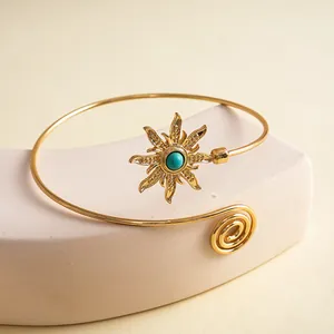 Detailopname van de retro gouden armband met zonnebloemdesign en turquoise steen.
