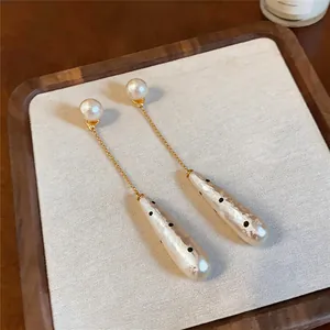 Macro view of vintage pearl drop earrings with elegant gold chain and polka dot pendant