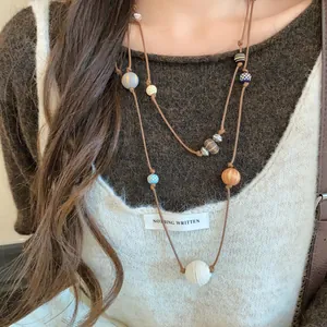 Détail en gros plan d'un collier à double rang en cuir avec des perles en bois variées