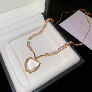 Elegante gouden ketting met een fonkelende harthanger en zirkonia in een geschenkdoos.