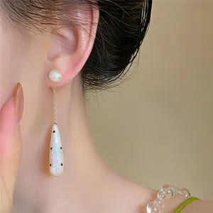 Close-up of vintage teardrop pearl drop earrings with elegant polka dot pattern