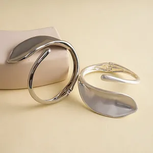 Detailansicht minimalistischer Blatt-Armreifen in glänzender und matter Silberoptik.
