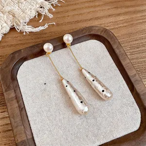 Detailed view of vintage pearl drop earrings with black polka dots on cream pendant.