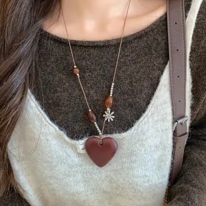 Vue détaillée d'un collier avec pendentif cœur, perles d'ambre et cordon en cuir brun