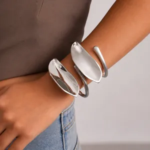 Nahaufnahme eines silbernen Metallarmreifs in Blattform am Handgelenk eines Models.