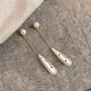 Close-up detail of vintage water-drop pearl earrings with black polka dot pendants