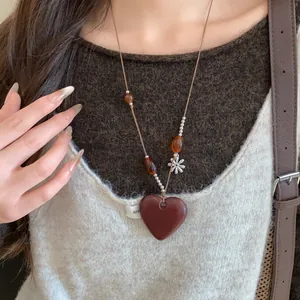 Gros plan d'un long collier de style chinois avec pendentif en cœur et perles en bois