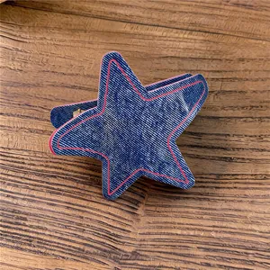 Vista detallada de una pinza para el cabello tipo estrella con textura denim y borde rosa.