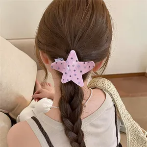 Vista detallada de una pinza para el pelo con forma de estrella rosa y lunares en trenza