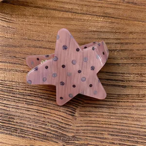 Imagen detallada de una pinza para el cabello de estrella rosa con patrón de puntos oscuros