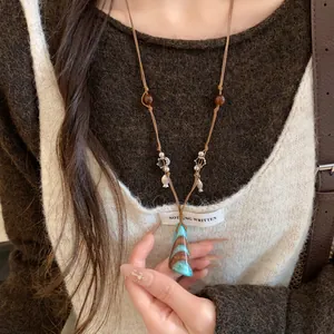 Vue détaillée d'un long collier avec des perles en bois et un pendentif turquoise