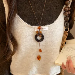 Gros plan d'une chaîne de pull de style nouveau chinois avec perles en bois et pendentifs.