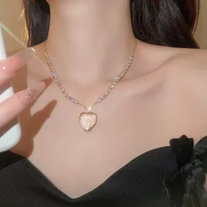 Close-up van een fonkelende hartjesketting met zirkonia gedragen door een model.