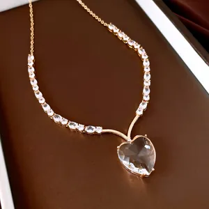 Detailed macro view of heart-shaped crystal pendant necklace with gold-plated chain.