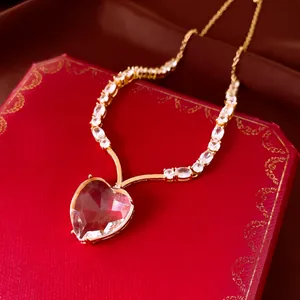 Close-up of elegant gold-plated heart crystal pendant necklace on luxury red box