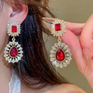 Elegant vintage palace style earrings featuring red teardrop rhinestones and a gold finish