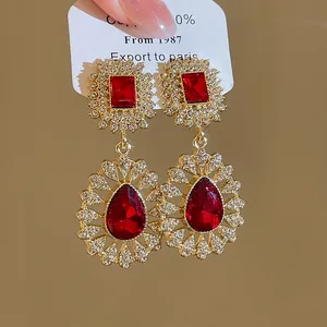 Detailed view of retro palace style earrings with red teardrop crystals and rhinestones