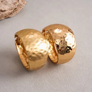 Detailed close-up of gold hammered metal bangles showing matte and glossy textures.