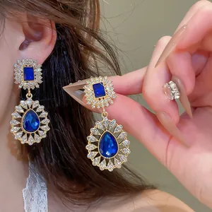 Close-up of vintage court style teardrop earrings with blue crystals and rhinestones.