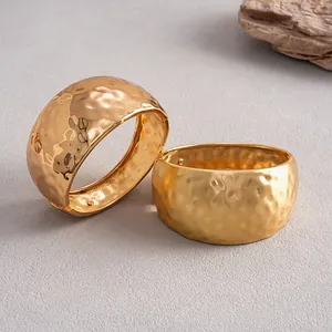 Detailed close-up showing shiny and matte gold hammered metal bangles with textures