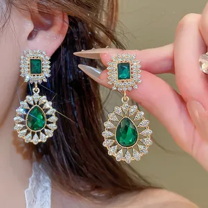 Close-up of luxury vintage emerald green teardrop earrings with sparkling rhinestones