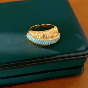 Dettaglio dell'anello aperto placcato oro 18 carati con pietre turchesi e texture.