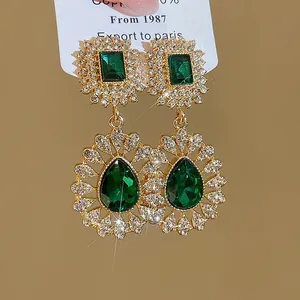 Close-up of vintage emerald green rhinestone water drop pendant earrings in gold-tone finish