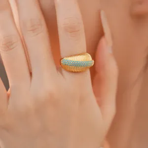 Dettaglio di un anello vintage placcato oro 18k con texture ondulata e turchesi.