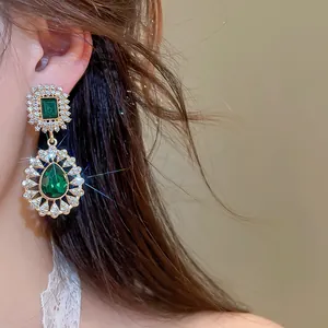 Detail view of elegant vintage emerald green drop earrings with sparkling rhinestone border