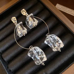 Détail de boucles d'oreilles pendantes en acrylique transparent sur un plateau en velours