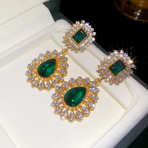 Detailed macro view of vintage emerald green teardrop earrings with shimmering diamond halo.