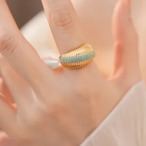 Primo piano di anello a coste placcato oro 18k con pietre turchesi sul dito