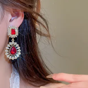 Close-up of vintage palace style gold earrings with red stones and sparkling rhinestones