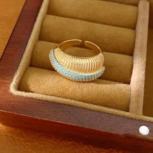 Dettaglio di un anello aperto dorato testurizzato con pietre turchesi in una scatola