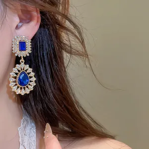 Detailed shot of vintage gold earrings with blue crystals and sparkling rhinestones.