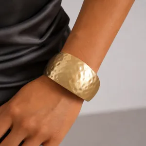 Exquisite hammered gold cuff bracelet with textured surface shown on a woman's wrist